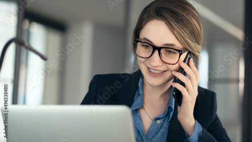 Young businesswoman talking mobile phone and using laptop computer in the office