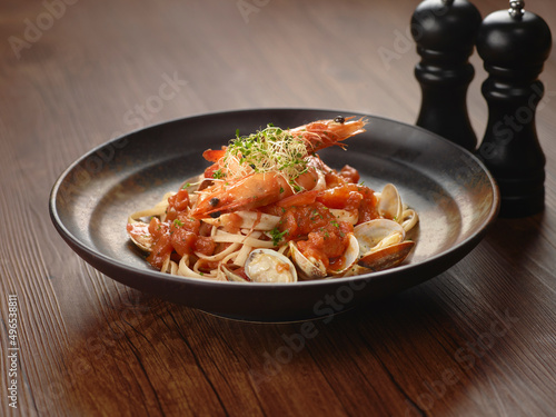 Seafood Marinara Pasta in a dish isolated on dark wooden table side view singapore food