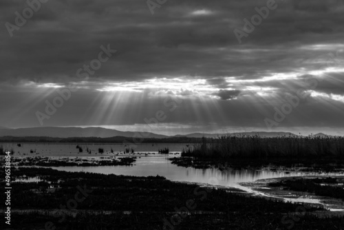 Sunrays at near sunset, with dark clouds in the background, above Trasimeno lake, Umbria, Italy