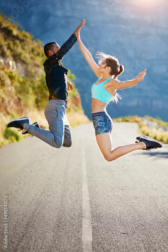 Theyre pumped up for fitness. Shot of a sporty young couple high fiving each other in midair outside.