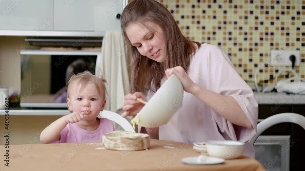 Little cute funny girl helping mother prepare pie cake in kitchen, baking homemade cookie together, happy family time Little cute funny girl helping mother prepare pie cake in kitchen, baking homemade cookie together, happy family time