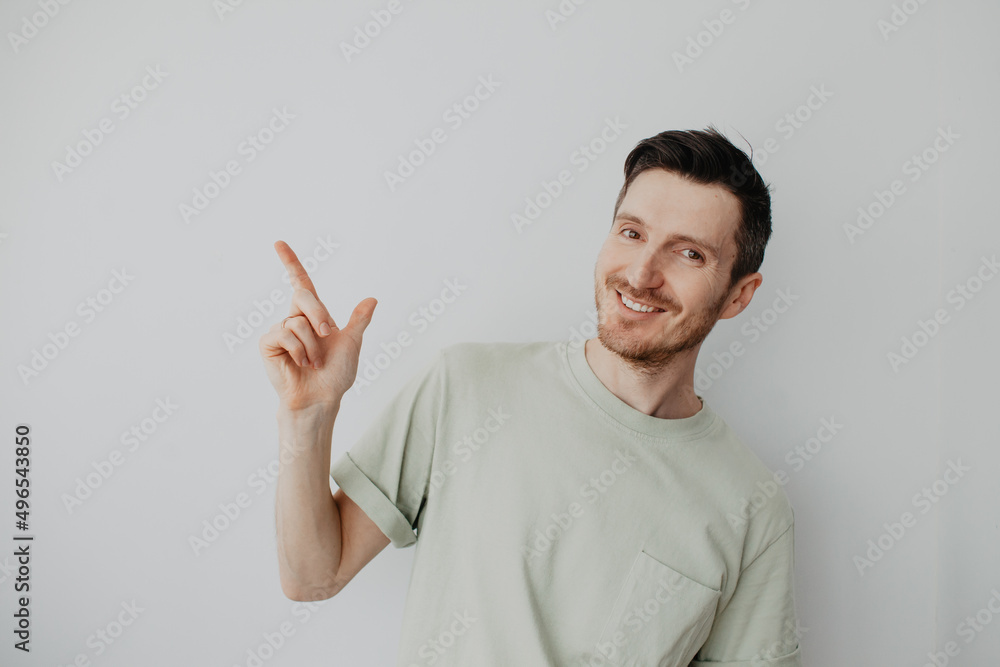 Handsome young man over grey wall with happy face pointing his finger Handsome young man over grey wall with happy face pointing his finger