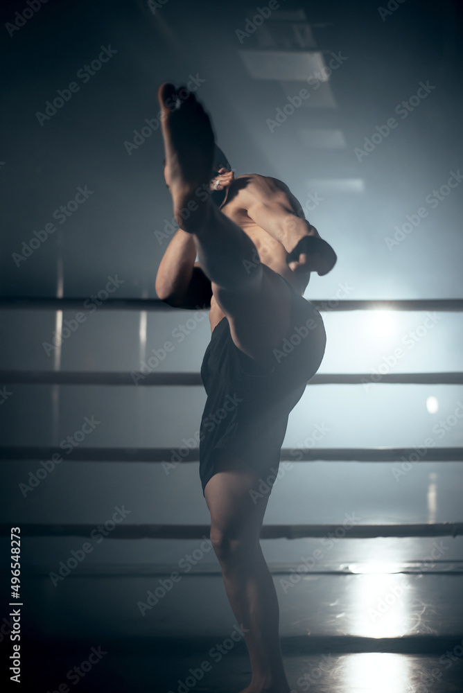 Muscular MMA fighter practicing kick, fight club concept. High quality photo Muscular MMA fighter practicing kick, fight club concept. High quality photo