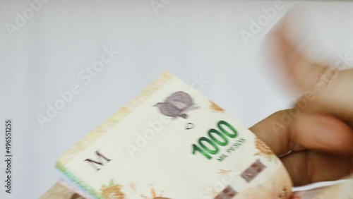 Caucasian female right hand counting argentine pesos banknotes money cash in a low angle, still shot and white background with indoor light
