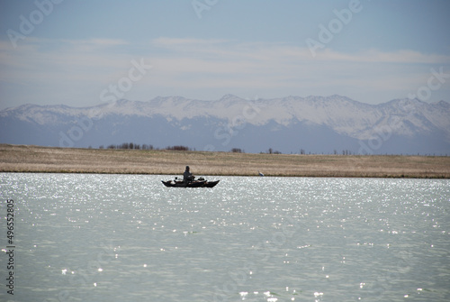 An angler in a pontoon on a mountain reservoir 