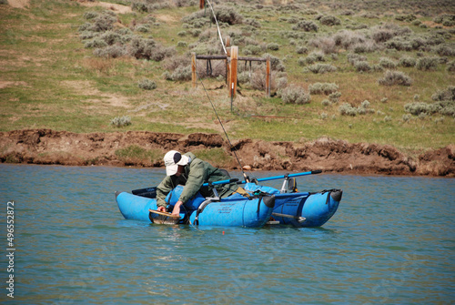 An angler in a pontoon netting a trout  photo