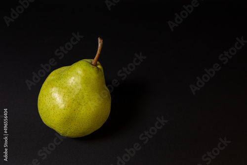 Ripe green pear on a dark background, late November pear variety. Whole fruit