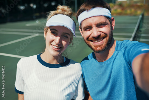 We found love on the tennis court. Portrait of a happy young couple taking selfies while playing tennis together outdoors on the court.