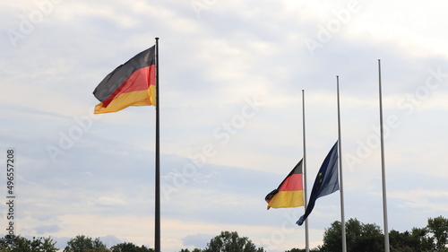 Flagge der Einheit sowie eine weitere Deutschland und EU Flagge, auf Halbmast, vor dem Reichstagsgebäude in Berlin.