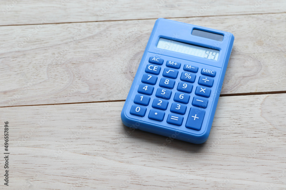 Blue office calculator for calculating numbers using solar energy isolated on wooden background closeup. Blue office calculator for calculating numbers using solar energy isolated on wooden background closeup.