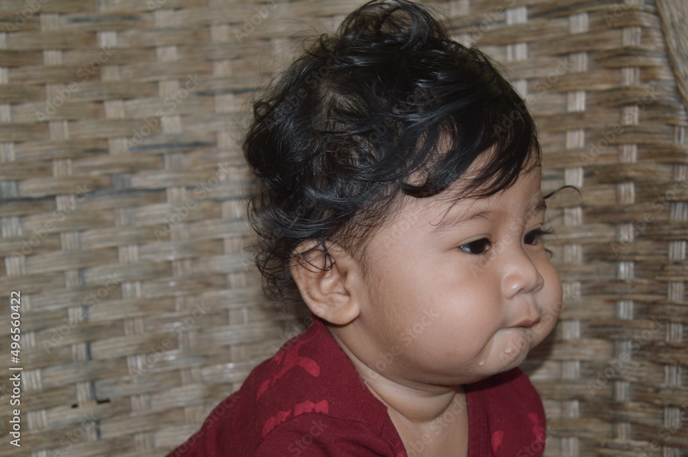 smiling and laughing expression of an asian baby boy wearing a maroon colored shirt sitting on a rattan chair smiling and laughing expression of an asian baby boy wearing a maroon colored shirt sitting on a rattan chair