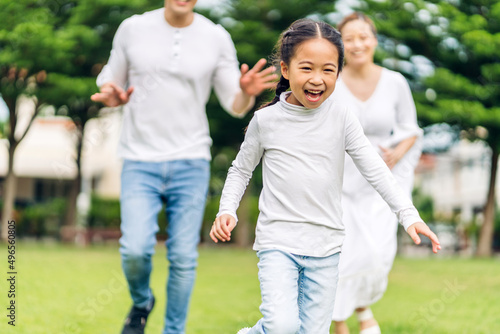 Portrait of enjoy happy love asian family father and mother run with cute little asian girl child smiling play and having fun moments good time in summer park at home © Art_Photo