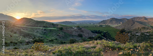 Panorama of hills, mountains, green valleys with citrus orchards and farming fields  as the sunsets in southern California countryside photo