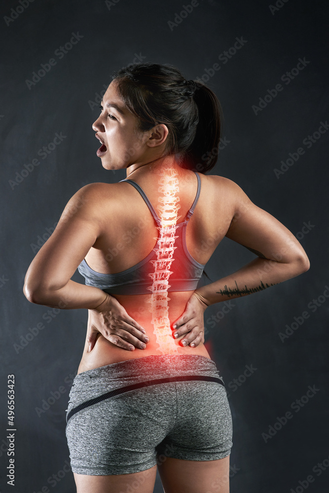 Injury is always a risk in sports. Rearview shot of a young sportswoman holding her back in anguish after injuring it. Injury is always a risk in sports. Rearview shot of a young sportswoman holding her back in anguish after injuring it.