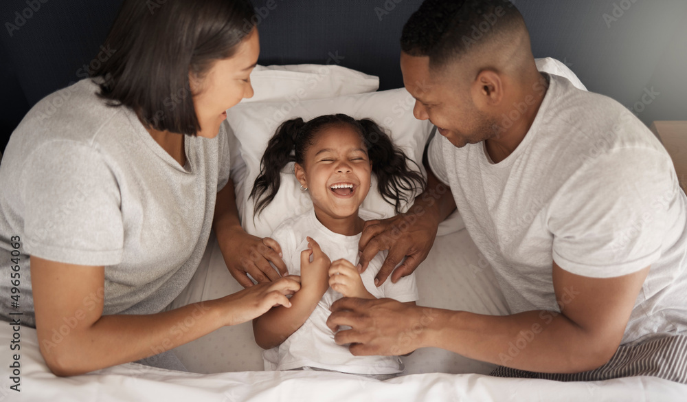 We know your weak spot. Shot of a young couple sitting in bed and bonding with their daughter by tickling her. We know your weak spot. Shot of a young couple sitting in bed and bonding with their daughter by tickling her.