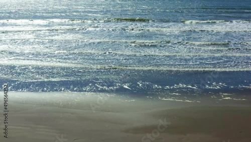On a summer evening on the seashore, a beautiful sea sunset, sea waves with white foam wash the sandy beach. Aerial sun setting over sea ocean, tropical seascape coastline from above.
