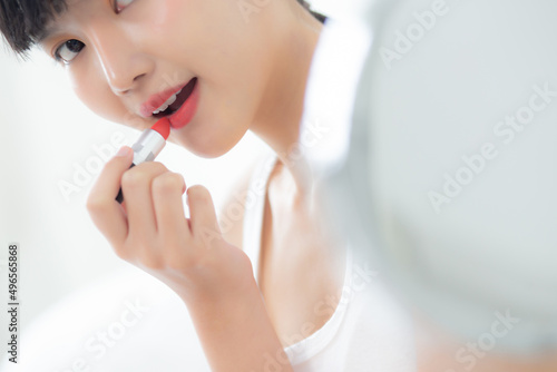 Beautiful young asian woman applying lipstick red on mouth  beauty girl looking facial at mirror for makeup cosmetic with lips elegance  make up with sexy of female  skin care and health concept.