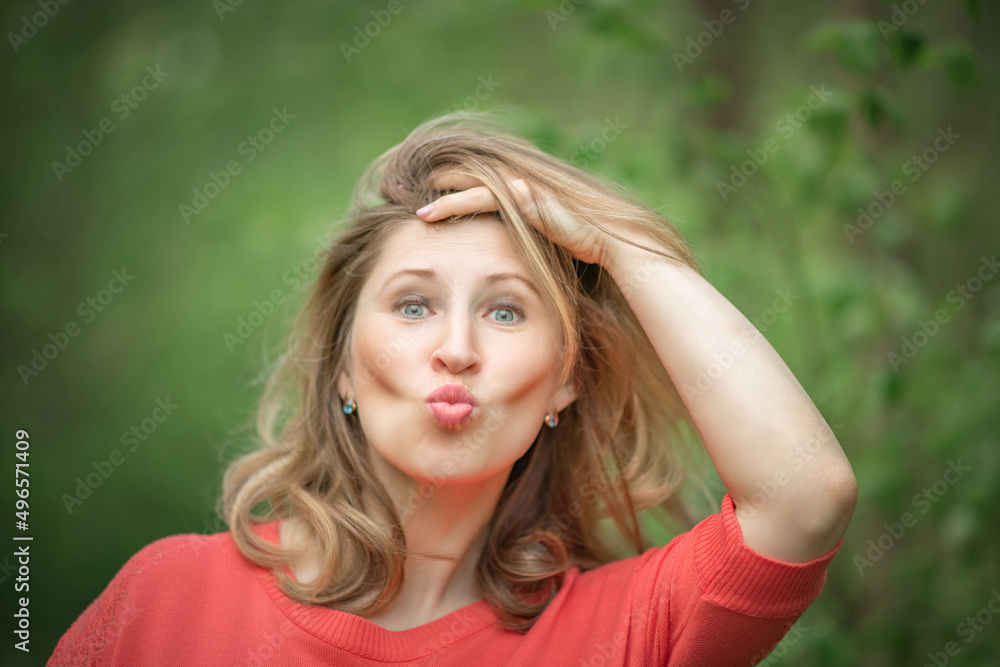 Beautiful blonde young woman in a pink blouse in the park.