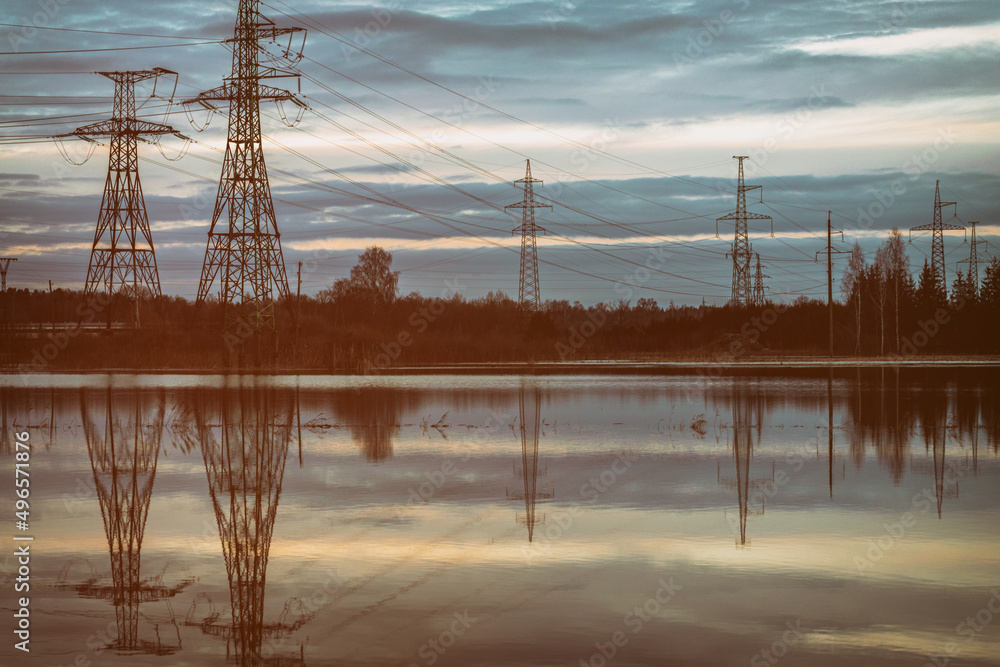 Spring floods on the field, electric pylons on overflown meadow. Vintage sunset colors