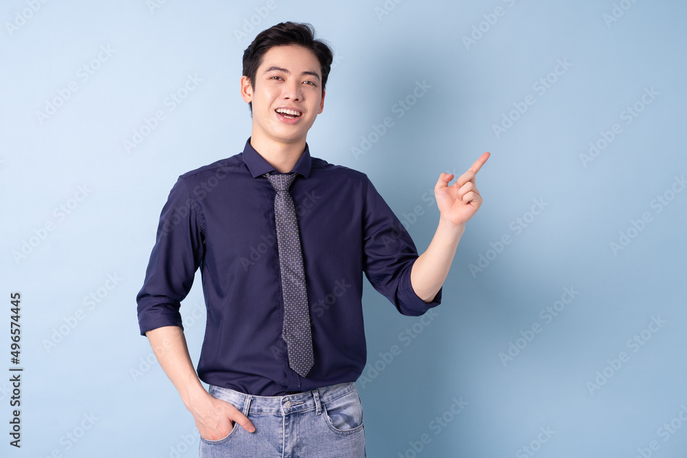 Portrait of young Asian businessman posing on blue background Portrait of young Asian businessman posing on blue background