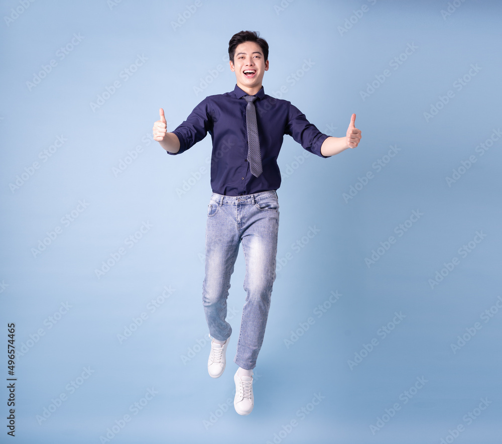 Full length image of young Asian businessman on blue background