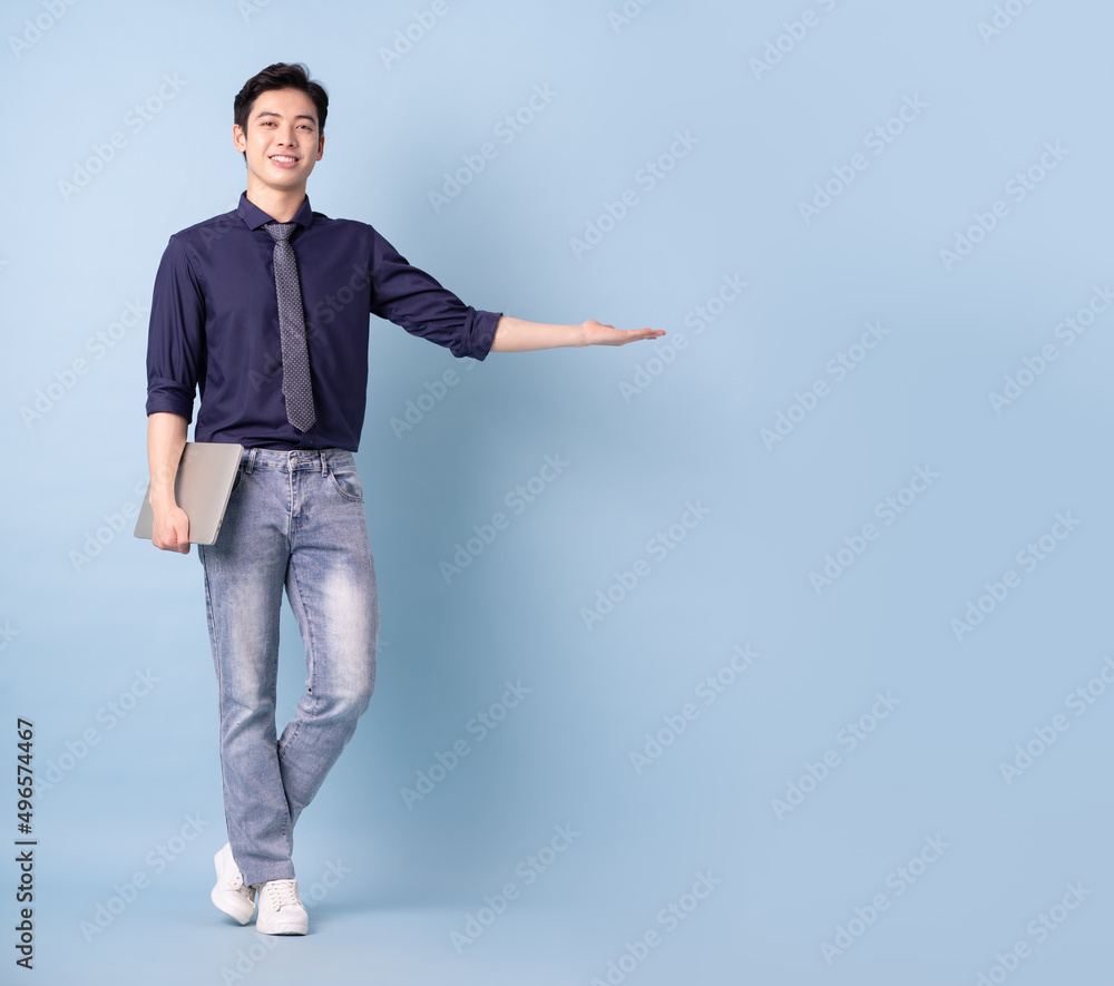 Full length image of young Asian businessman on blue background Full length image of young Asian businessman on blue background