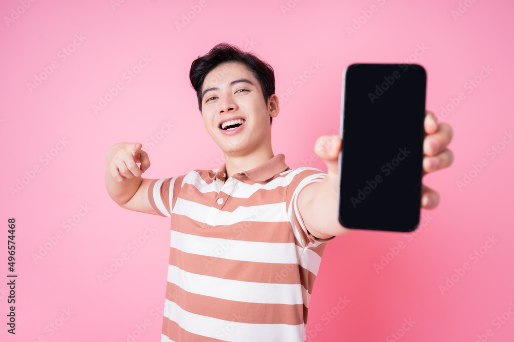 Portrait of young Asian man using smartphone on pink background Portrait of young Asian man using smartphone on pink background