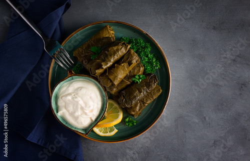 Dolma, cabbage rolls, grape leaves with filling, white sauce, lemon and herbs, rustic, selective focus, no people, photo