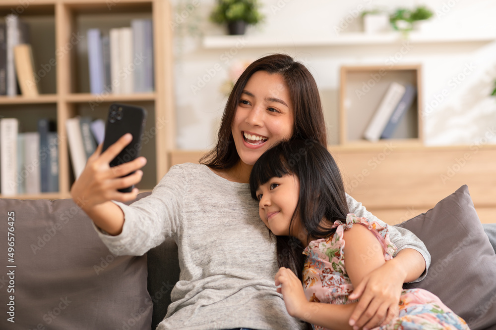 Foto de Asian mom and her kid are calling on smartphone. Both happy