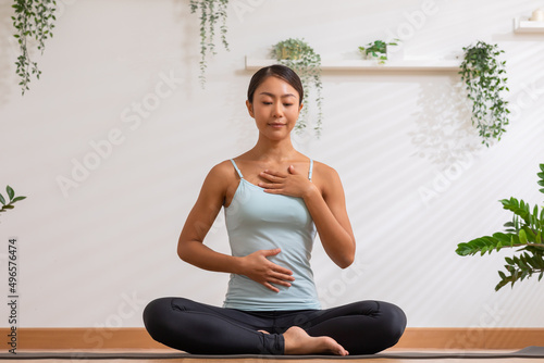 Asian woman doing breathing exercise before practice yoga.Healthy female inhaling and exhaling to deep breath exercise for control and balance life with yoga meditation decrease stress, relax her mind photo