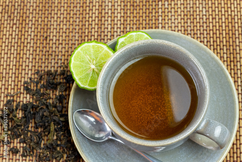 Bergamot tea or Earl Grey tea in ceramic cup and fresh bergamot fruit with sliced on mat, top view.
