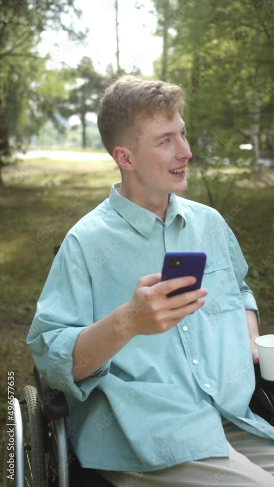 An adult disabled man sitting in a wheelchair in the park, laughing and taking a panoramic photo An adult disabled man sitting in a wheelchair in the park, laughing and taking a panoramic photo