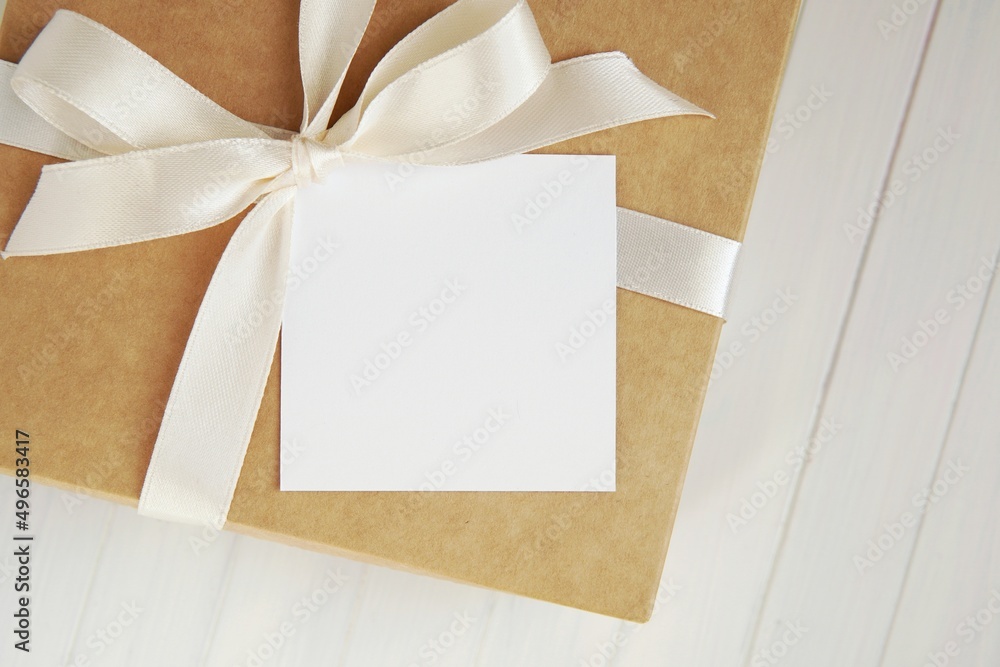 Small blank square card mockup on gift box with white ribbon, name card mock up for Christmas or wedding design. Small blank square card mockup on gift box with white ribbon, name card mock up for Christmas or wedding design.