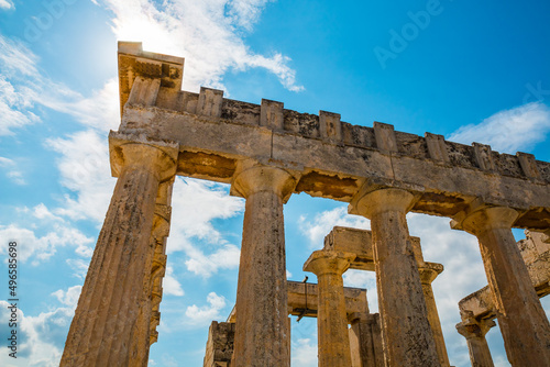 View on ruins Temple of Aphaea, Aegina, Greece with clouds and sun rays in the background