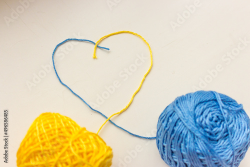 Yellow and blue threads in heart shape. Ukrainian national colors. Patriotic ukrainian background. Love Ukraine concept. Creative needlework. Love symbol. Handcraft background. Hobby concept. 