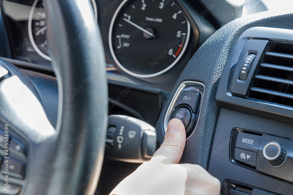 Finger pressing the engine start button of a car Finger pressing the engine start button of a car