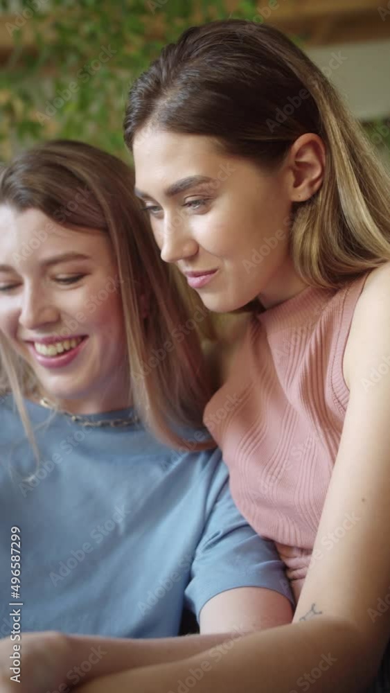 Two young beautiful ladies are searching through the Internet on the laptop, discussing and smiling Two young beautiful ladies are searching through the Internet on the laptop, discussing and smiling