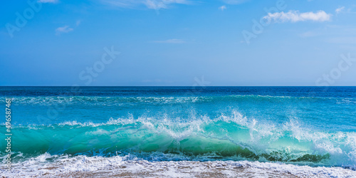 Fototapeta Naklejka Na Ścianę i Meble -  A beautiful blue wave rises before crashing onto the sand of the beach. View of the Atlantic Ocean in sunny weather in Florida.
