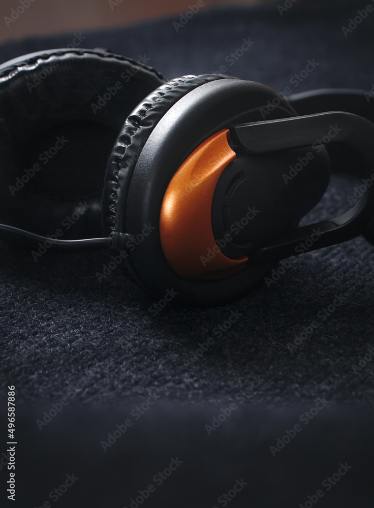 Background for music. Large headphones on a black background with a beautiful light on top, close-up