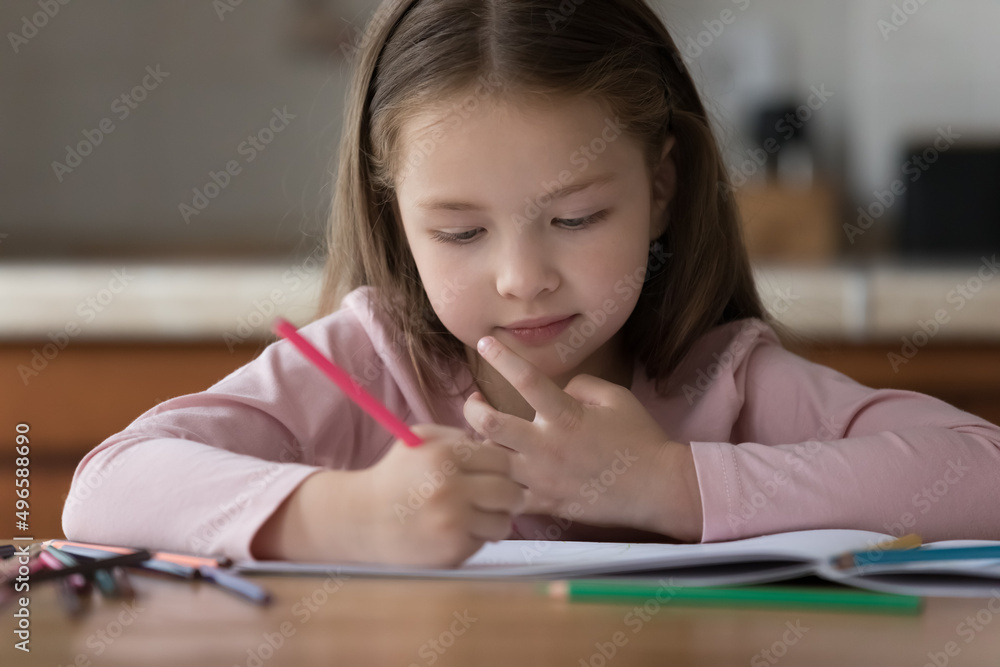 Sweet preschool girl kid using colored pencils, drawing in paper album, developing creative artistic skills. Little child engaged in home activities, sitting at kitchen table Sweet preschool girl kid using colored pencils, drawing in paper album, developing creative artistic skills. Little child engaged in home activities, sitting at kitchen table