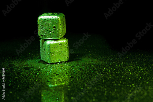 Fototapeta Naklejka Na Ścianę i Meble -  Green stainless steel cubes simulating ice for cooling drinks on a black surface with a reflection.