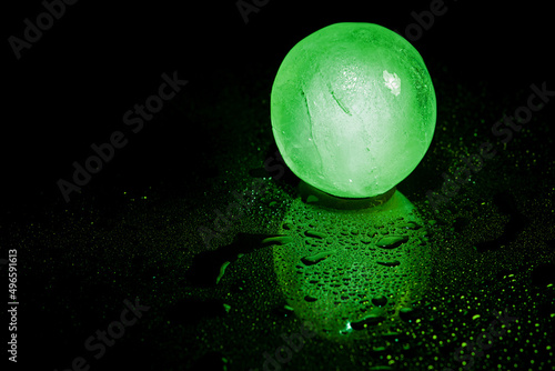 Green ice ball reflection on black background. © peterkai
