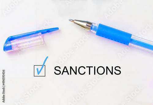 check mark on the word sanctions and crossed lines and pen. Closeup, concept