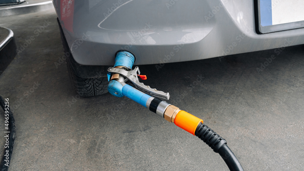 Gas station. Pump fuel petrol in tank car. Gasoline oil in nozzle. Close-up of the hand and the fuel gun. Blurred background. Gas station. Pump fuel petrol in tank car. Gasoline oil in nozzle. Close-up of the hand and the fuel gun. Blurred background.