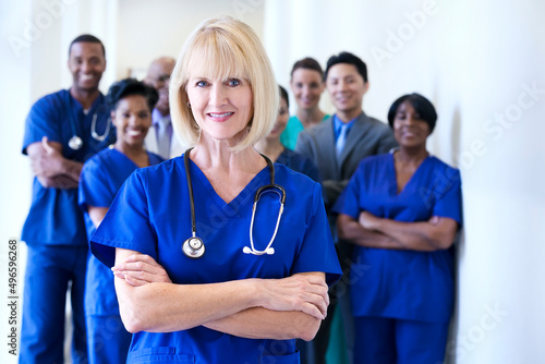 Smiling portrait female Caucasian nurse with multi ethnic team in medical centre photo