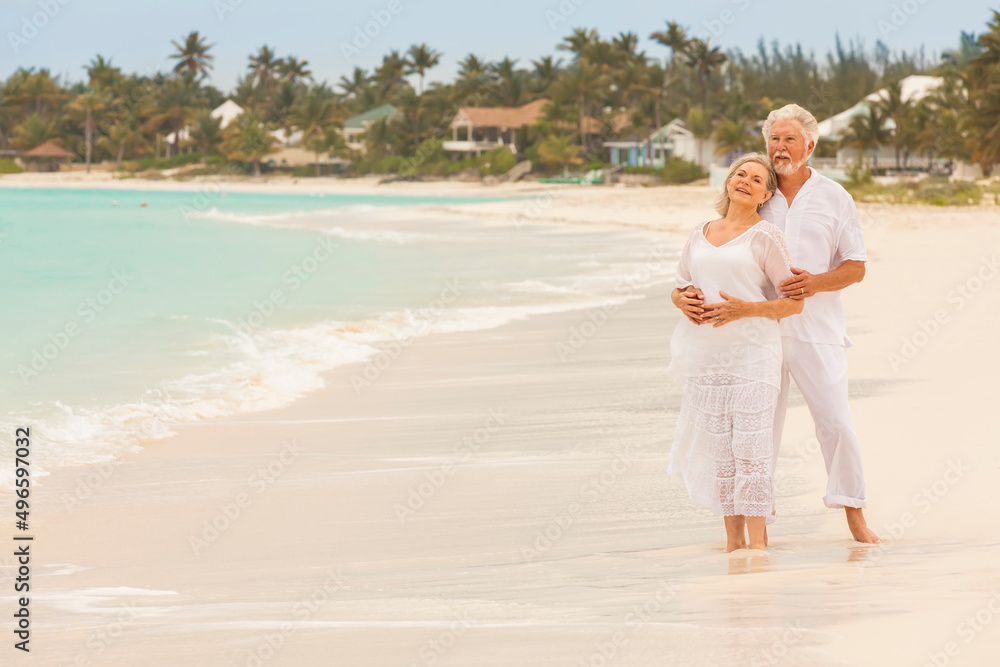 Retired Caucasian couple in white clothes on a Caribbean beach Retired Caucasian couple in white clothes on a Caribbean beach