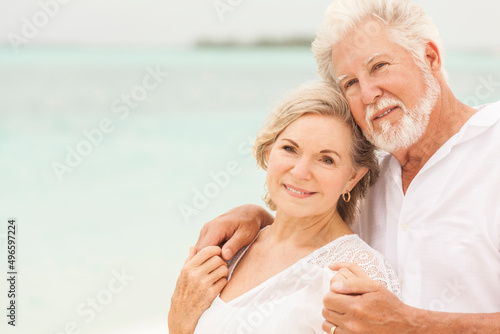 Smiling senior Caucasian couple in white living an island lifestyle on beach