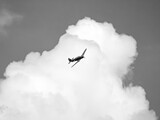 czarno białe zdjęcie starego jednopłatowca na tle chmur podczas pokazu lotniczego