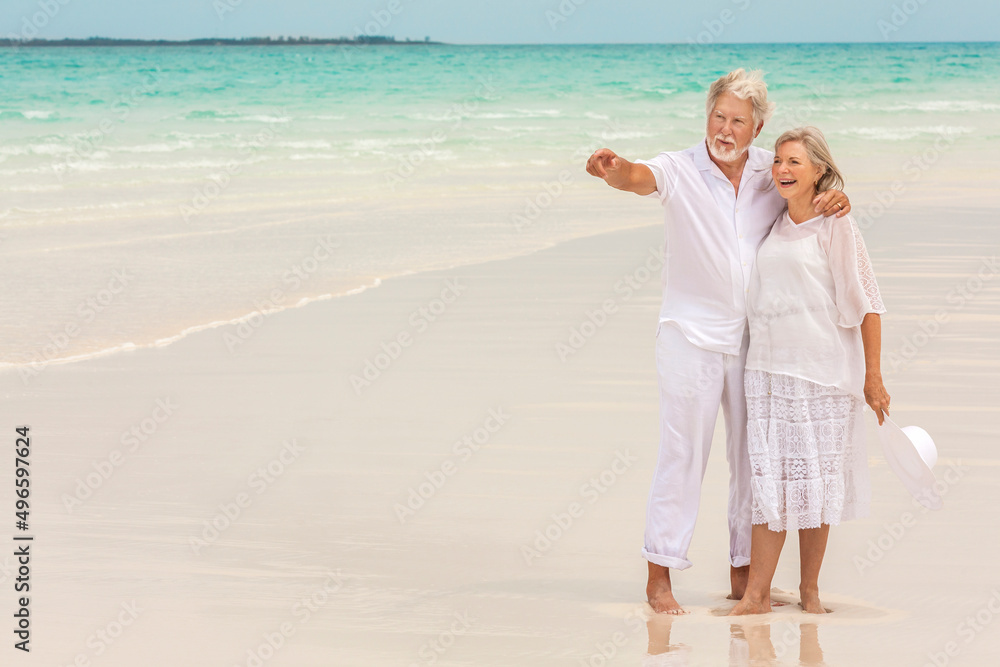 Barefoot Caucasian senior couple in white clothes on a travel resort beach Barefoot Caucasian senior couple in white clothes on a travel resort beach