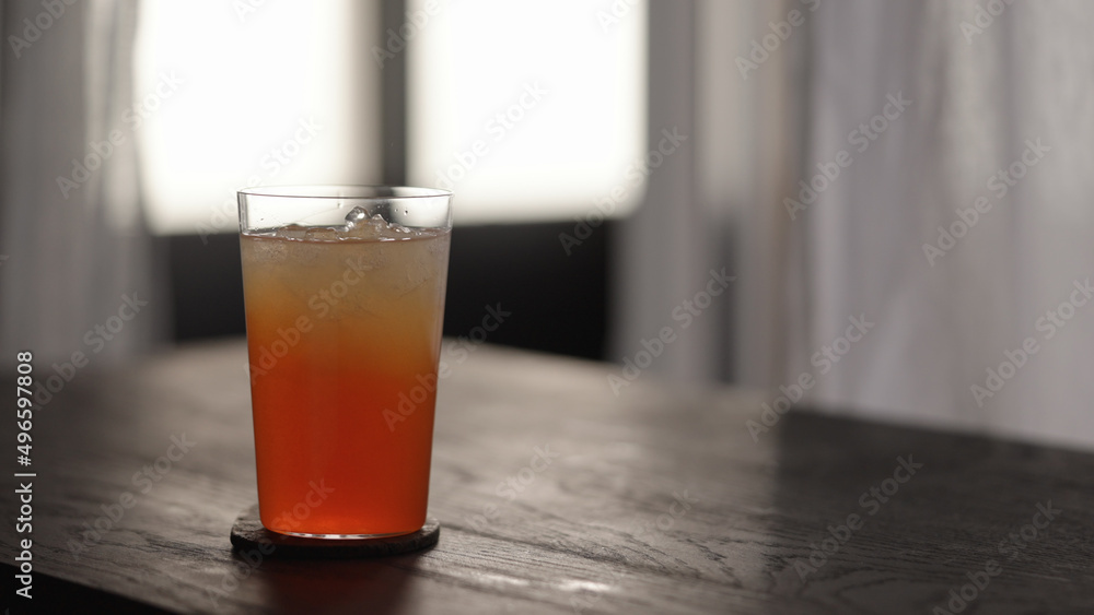 orange syrup in lemonade in tumbler glass with crushed ice on wood table orange syrup in lemonade in tumbler glass with crushed ice on wood table